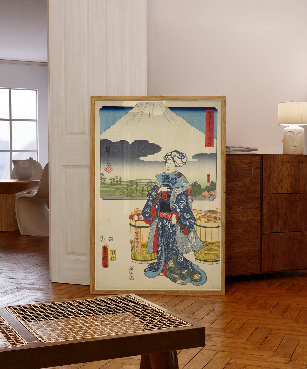 Framed art print of Fifty-three Stations by Two… by Utagawa Hiroshige & Utagawa Kunisada, in a light wood frame leaning in a warm room with a parquet floor