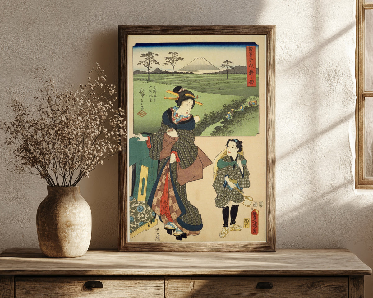 Framed art print of Fifty-three Stations by Two… by Utagawa Hiroshige & Utagawa Kunisada, in a dark wood frame leaning on a rustic console beside dried flowers