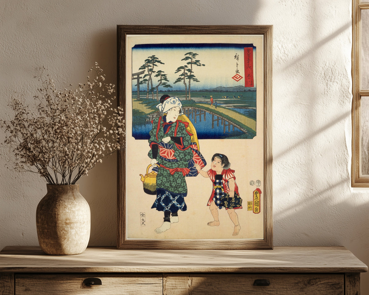 Framed art print of Fifty-three Stations by Two… by Utagawa Hiroshige & Utagawa Kunisada, in a dark wood frame leaning on a rustic console beside dried flowers