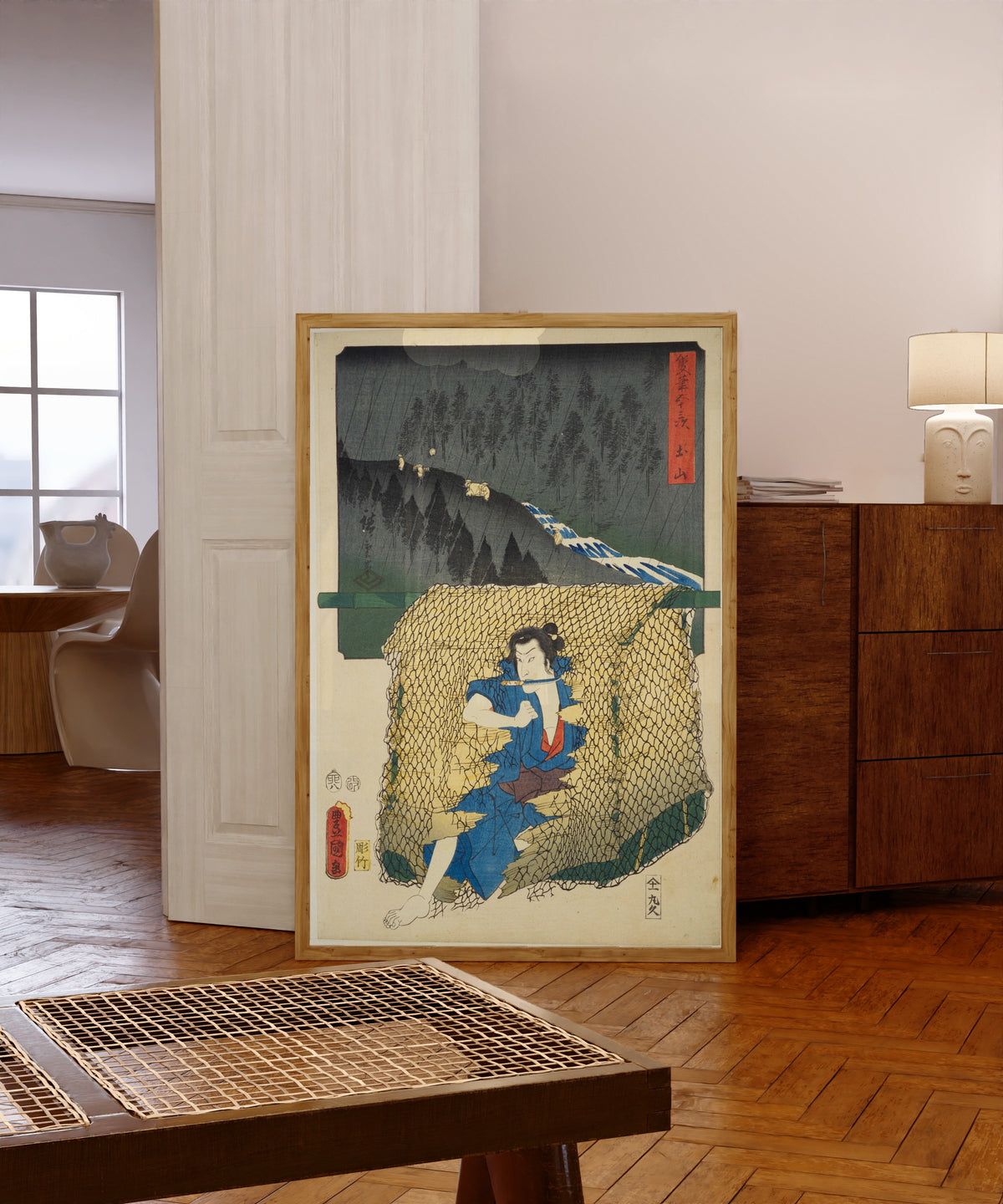 Framed art print of Fifty-three Stations by Two… by Utagawa Hiroshige & Utagawa Kunisada, in a light wood frame leaning in a warm room with a parquet floor