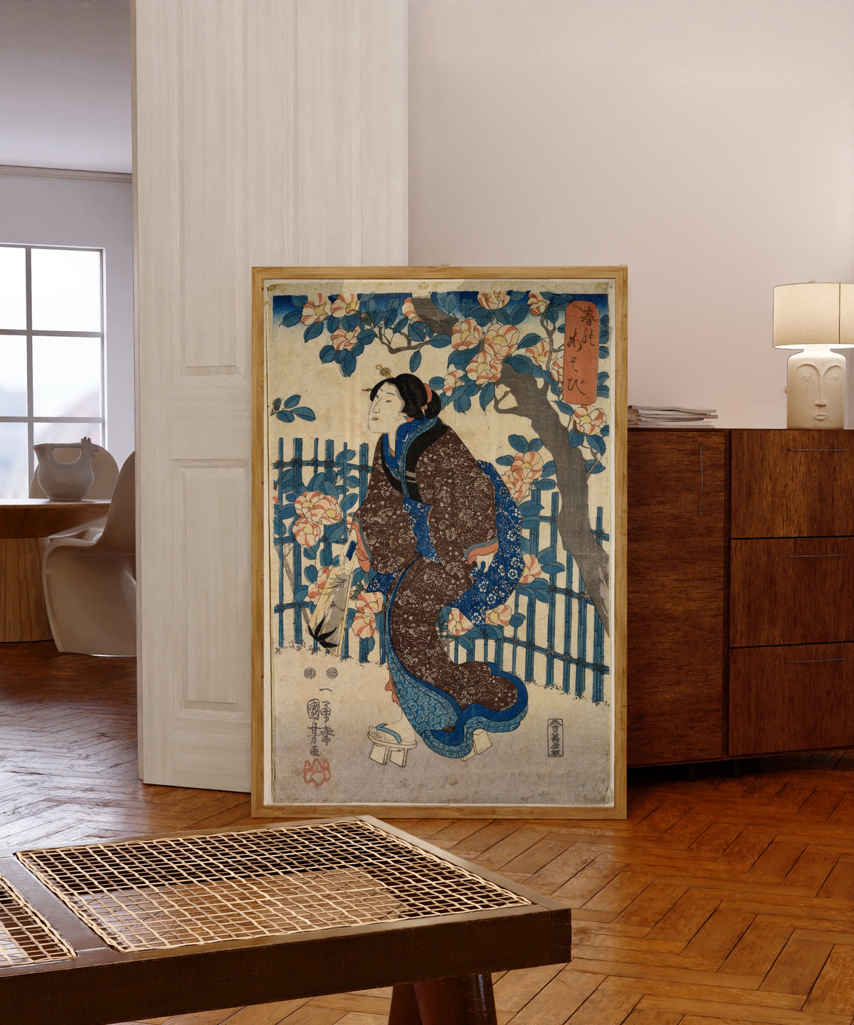 Framed art print of Games of Spring by Utagawa Kuniyoshi, in a light wood frame leaning in a warm room with a parquet floor