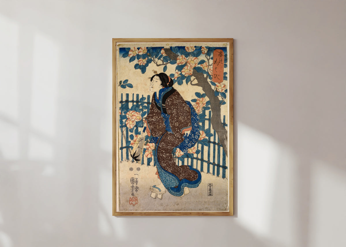 Framed art print of Games of Spring by Utagawa Kuniyoshi, in a light wood frame on a sunlit white wall