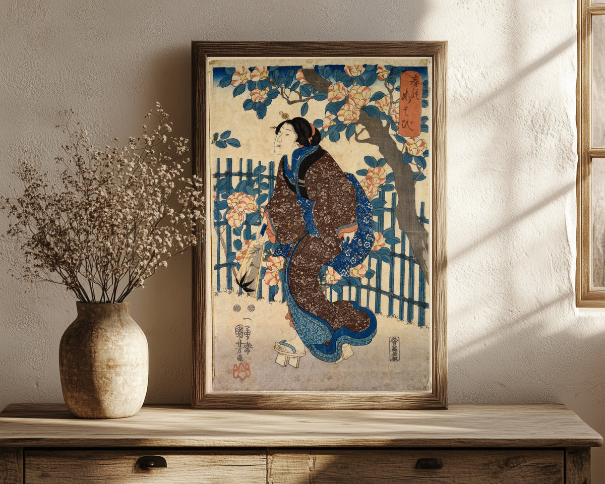 Framed art print of Games of Spring by Utagawa Kuniyoshi, in a dark wood frame leaning on a rustic console beside dried flowers