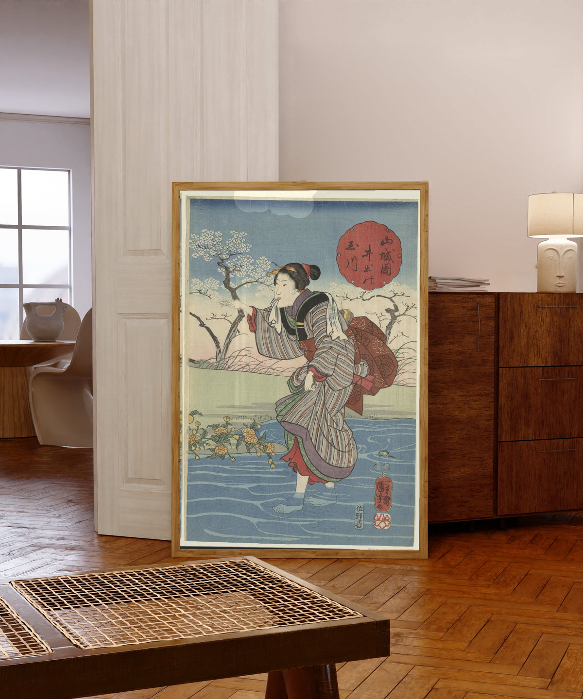 Framed art print of The Ide Tama River in Yamashiro Province by Utagawa Kuniyoshi, in a light wood frame leaning in a warm room with a parquet floor