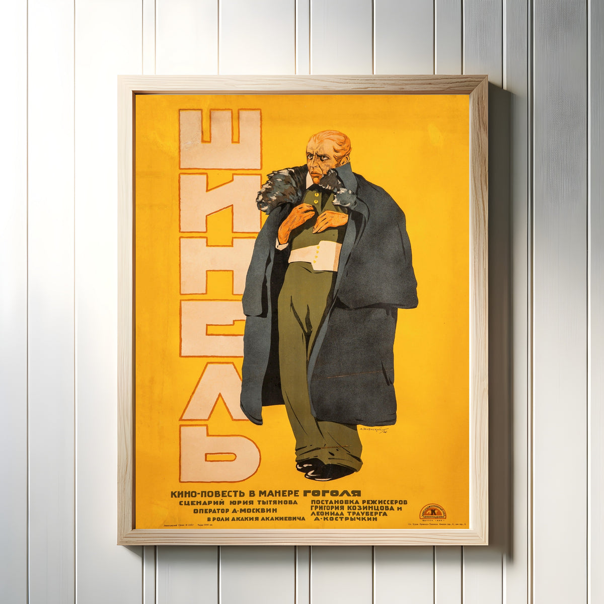 Framed art print of The Overcoat (Gogol) by Alexander Zelensky, in a light wood frame on a white panelled wall