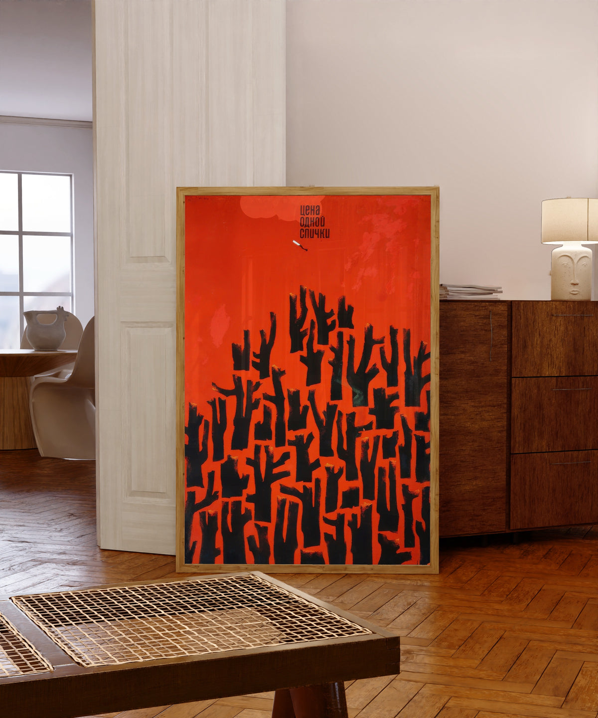 Framed art print of The Price of One Match by V. Strimaitis, in a light wood frame leaning in a warm room with a parquet floor