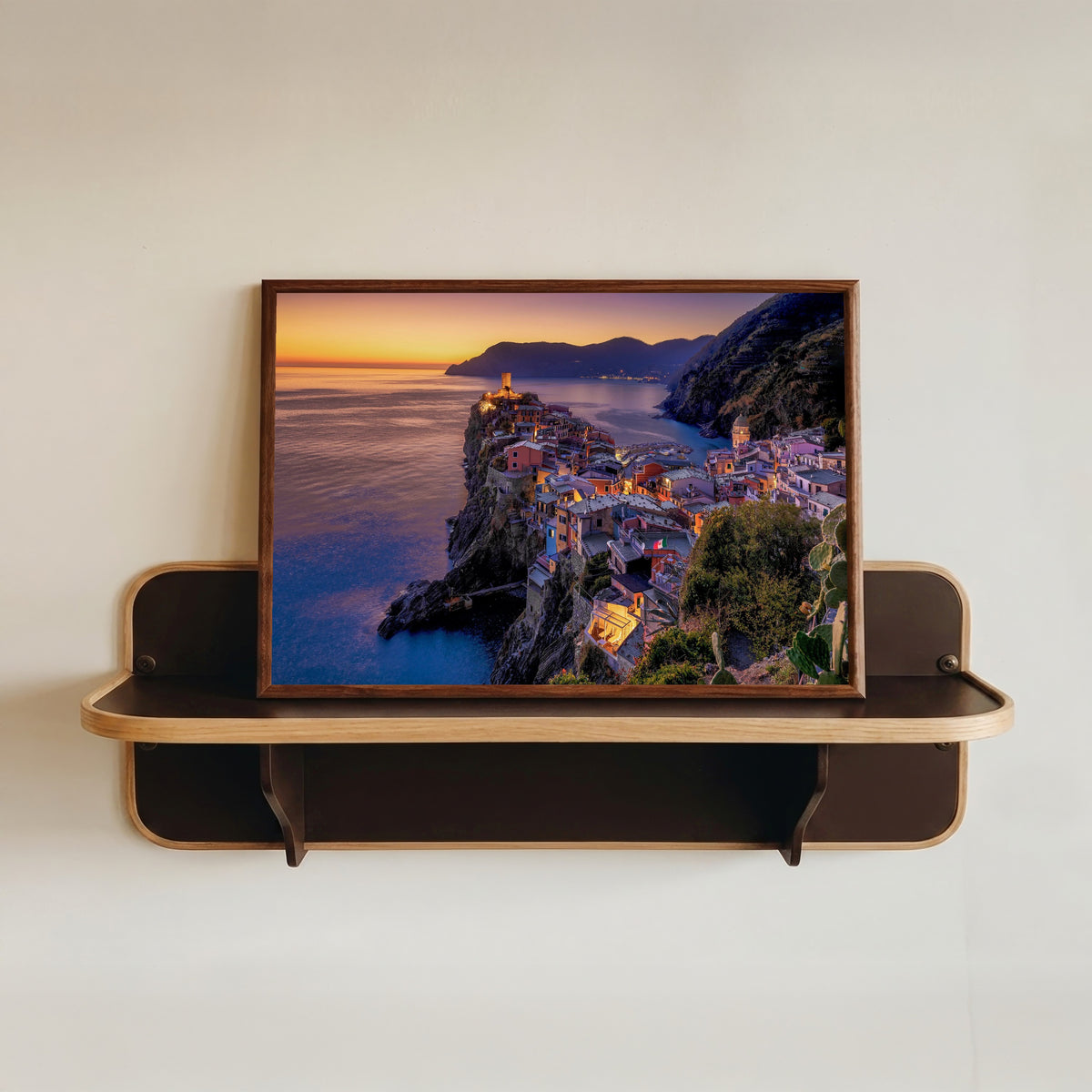 Framed art print of Vernazza Sunset by Pablo Meilán Campagnale, in a dark wood frame resting on a wall shelf