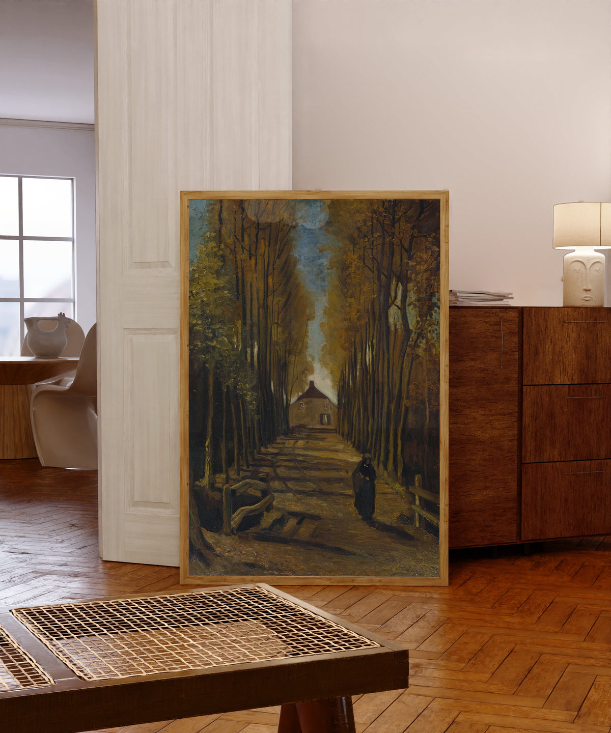 Framed art print of Avenue of Poplars in Autumn by Vincent van Gogh, in a light wood frame leaning in a warm room with a parquet floor