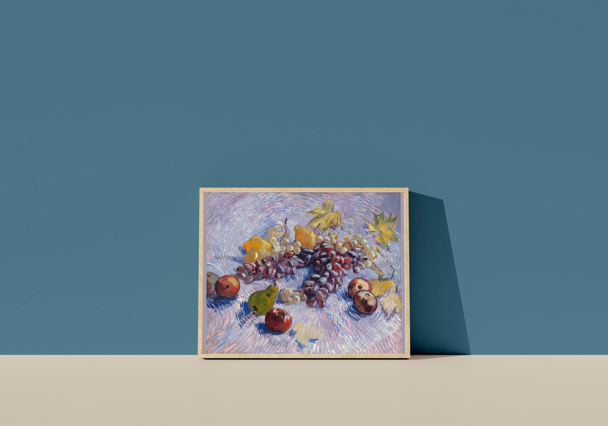 Framed art print of Grapes, Lemons, Pears and Apples by Vincent van Gogh, in a light wood frame leaning on a blue wall