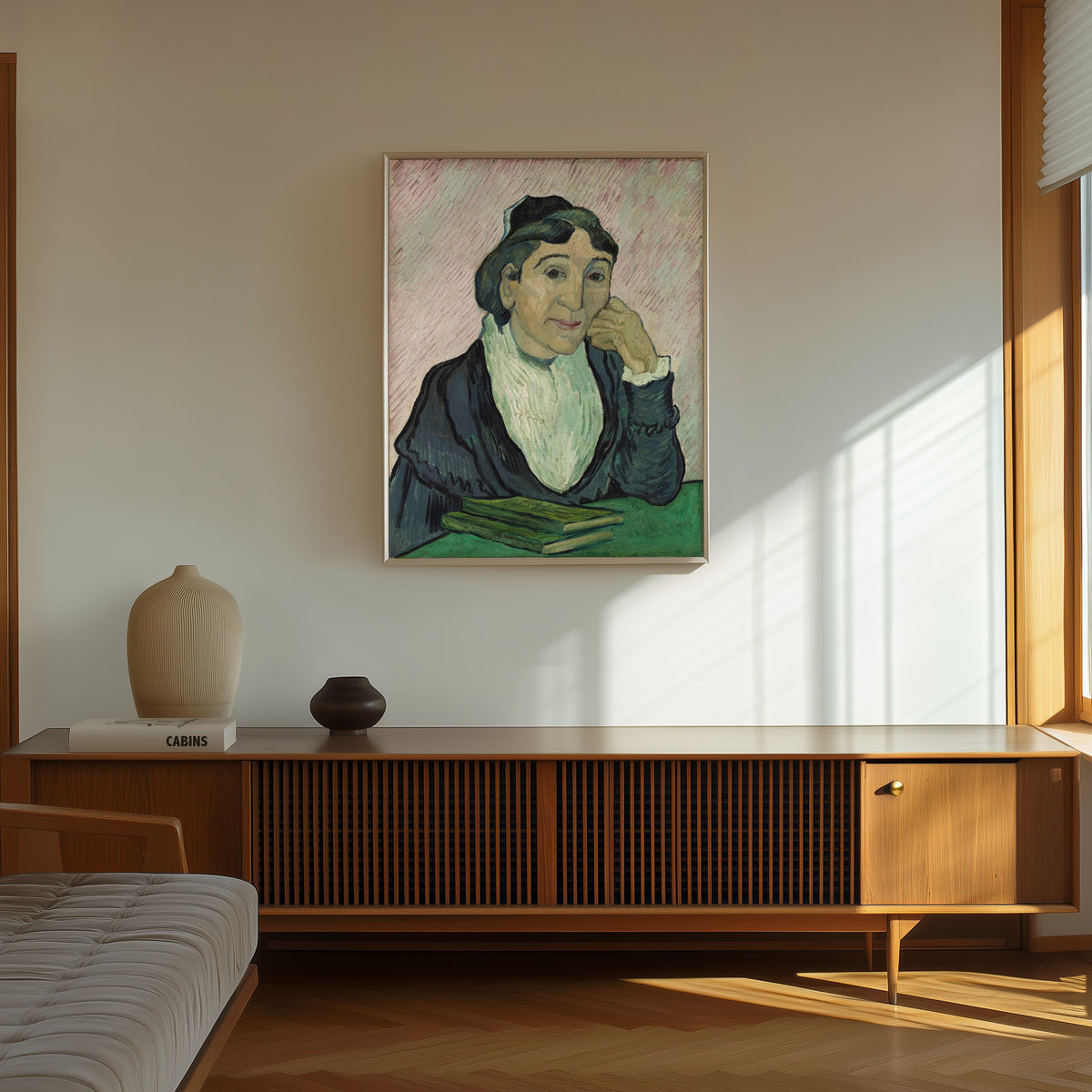 Framed art print of L'Arlésienne (Madame Ginoux) by Vincent van Gogh, in a thin light frame on a sunlit wall above a wooden sideboard