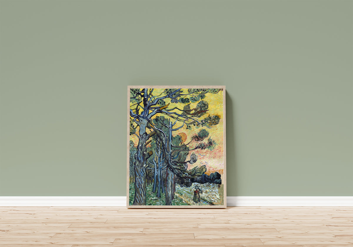 Framed art print of Pine Trees at Sunset by Vincent van Gogh, in a light wood frame leaning on a sage green wall above a wooden floor