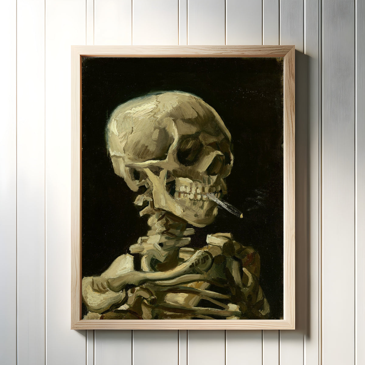 Framed art print of Skull with Burning Cigarette by Vincent van Gogh, in a light wood frame on a white panelled wall