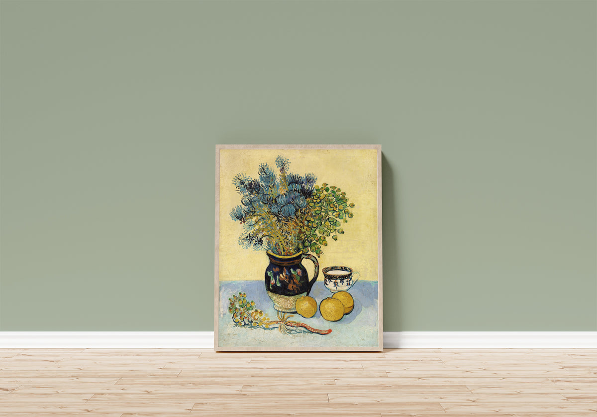 Framed art print of Still Life by Vincent van Gogh, in a light wood frame leaning on a sage green wall above a wooden floor