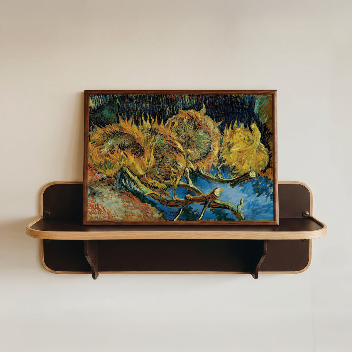 Framed art print of Sunflowers by Vincent van Gogh, in a dark wood frame resting on a wall shelf