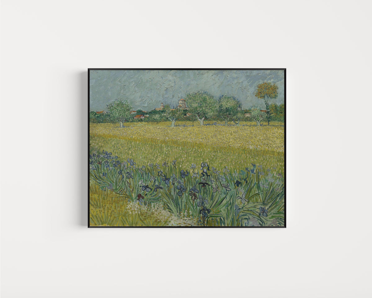 Framed art print of View of Arles with Irises by Vincent van Gogh, in a slim black frame on a plain white wall