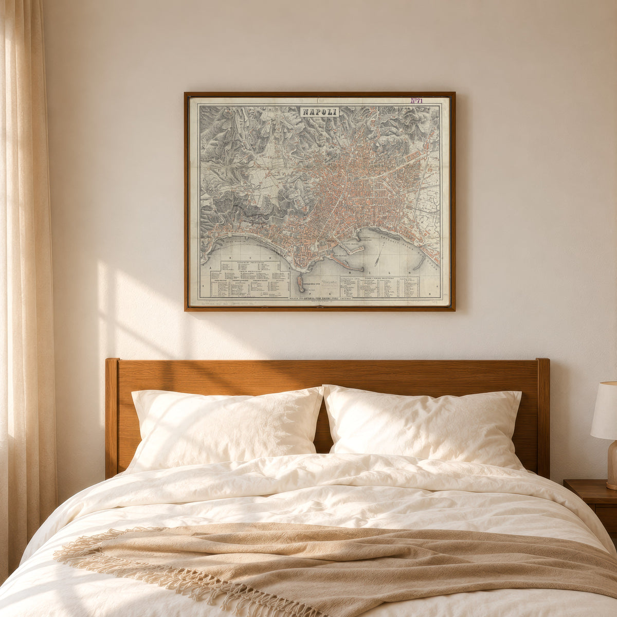 Framed art print of Map of Naples, in a slim wood frame above a bed in a sunlit bedroom