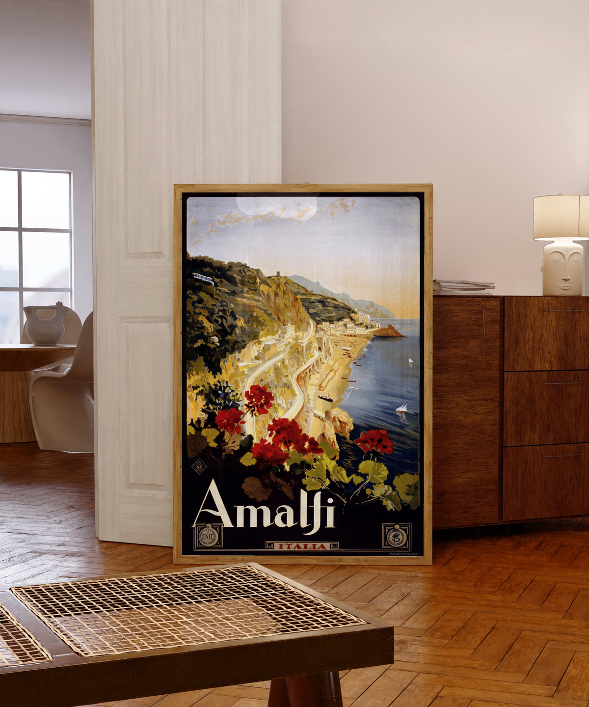 Framed art print of Italian Travel Poster Print, in a light wood frame leaning in a warm room with a parquet floor