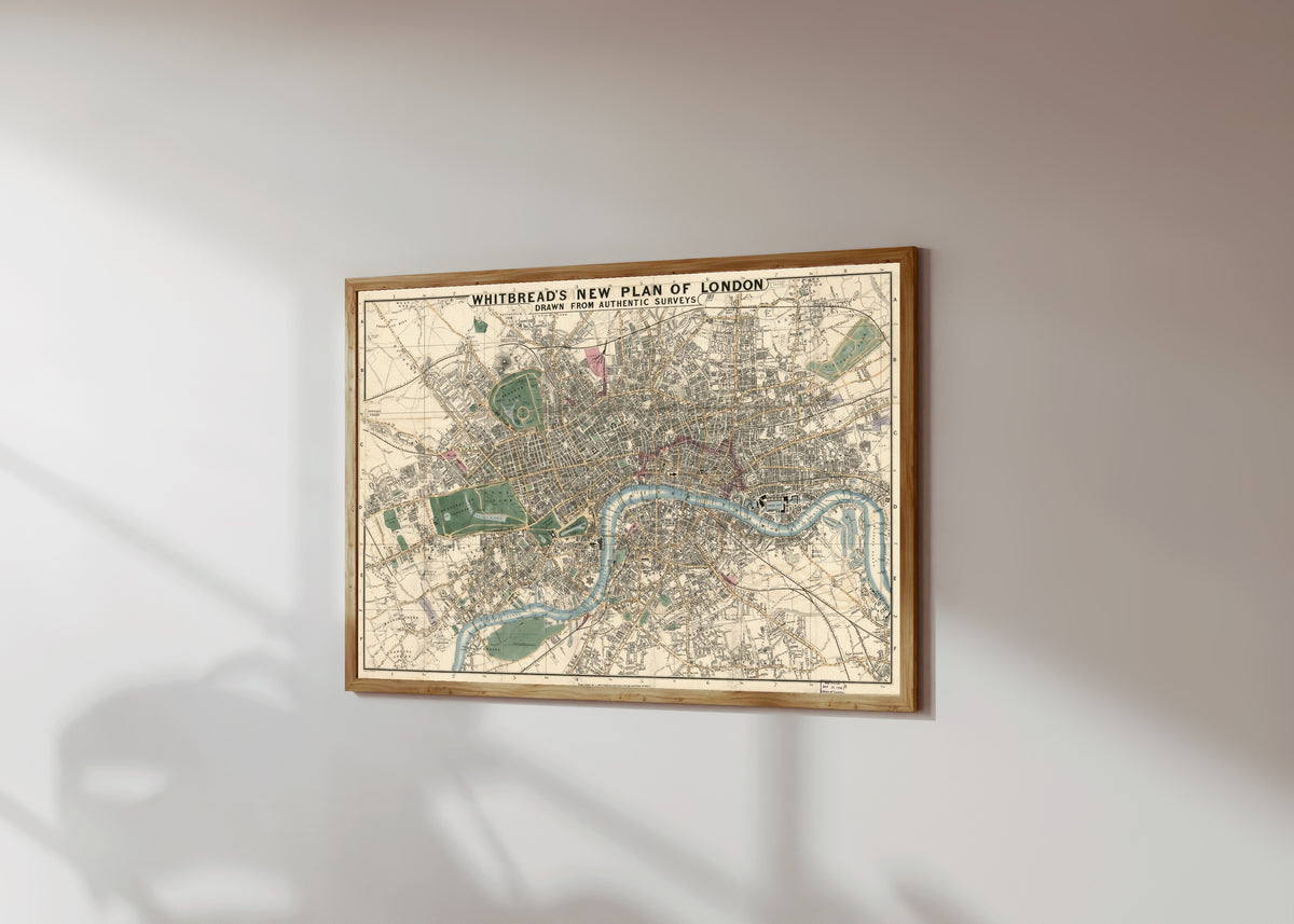 Framed art print of Whitbread's New Plan of London, in a light wood frame on a sunlit white wall, seen at a slight angle