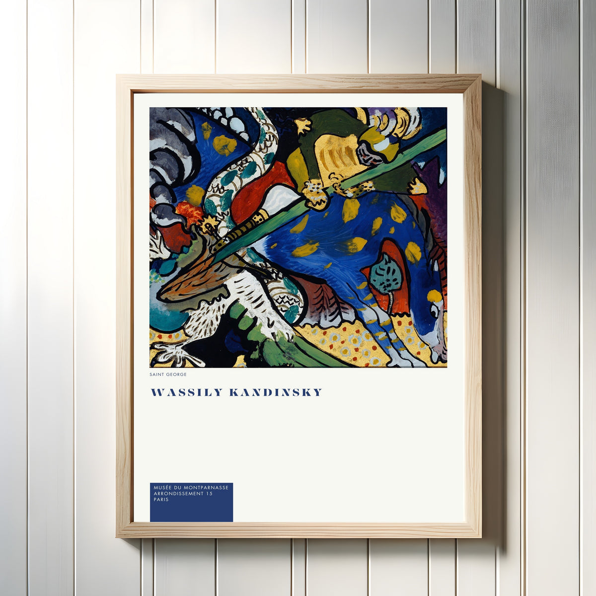 Framed art print of St. George by Wassily Kandinsky, in a light wood frame on a white panelled wall
