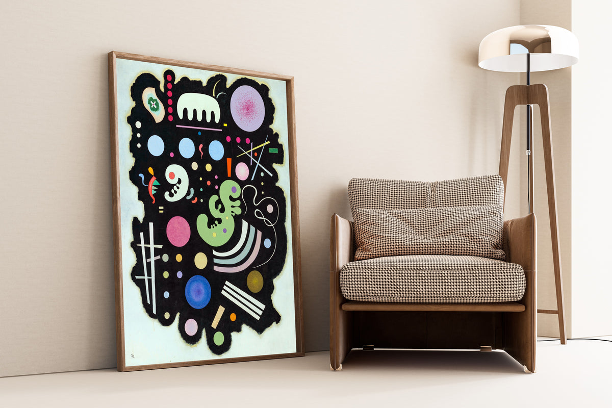 Variegated Black by Wassily Kandinsky — framed and leaning against a wall beside an armchair and a floor lamp