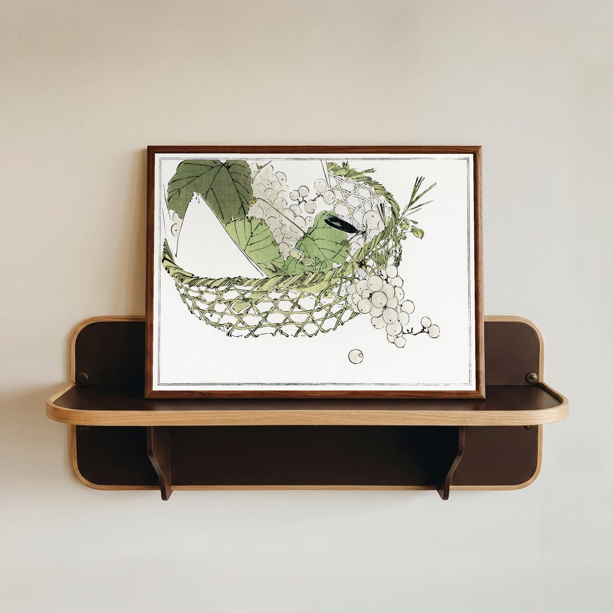 Framed art print of Basket of grapes from Seitei Kacho Gafu (1890–1891) by Watanabe Seitei, in a dark wood frame resting on a wall shelf
