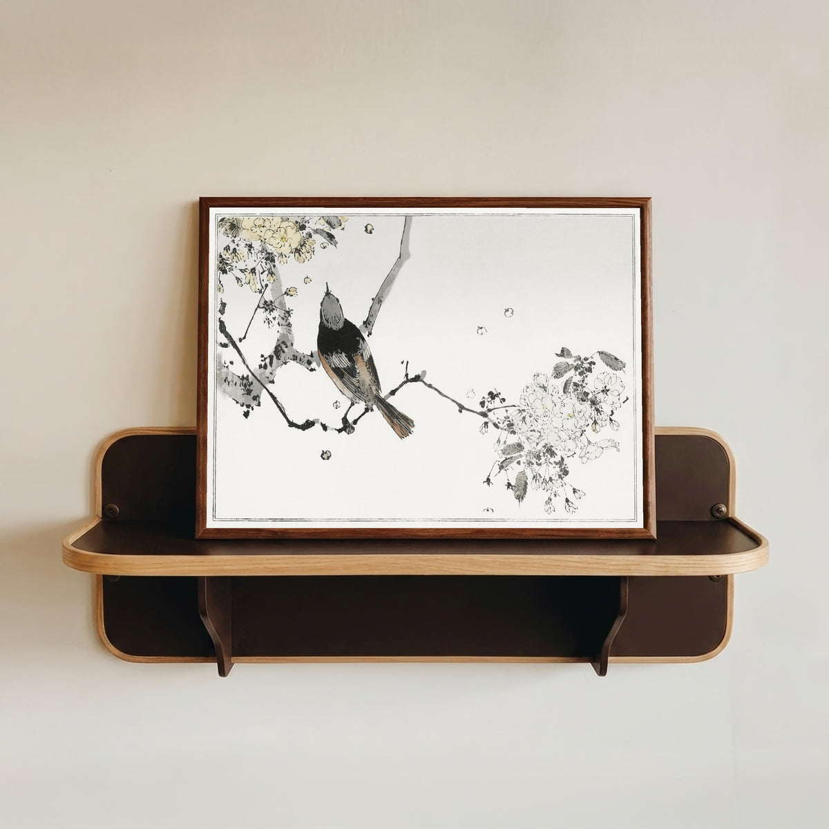 Framed art print of Bird on a Flowering Branch by Watanabe Seitei, in a dark wood frame resting on a wall shelf