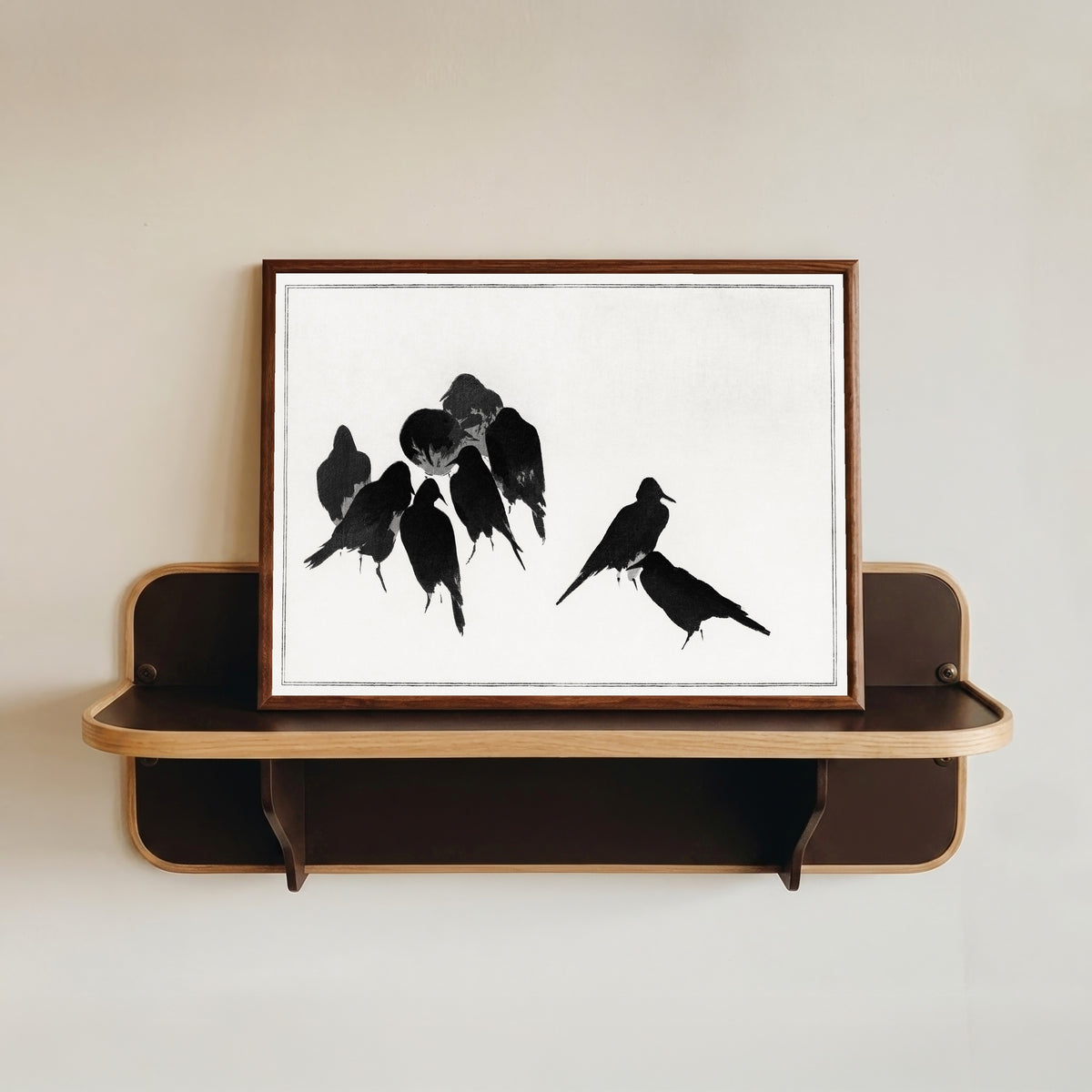 Framed art print of Japanese Crows by Watanabe Seitei, in a dark wood frame resting on a wall shelf