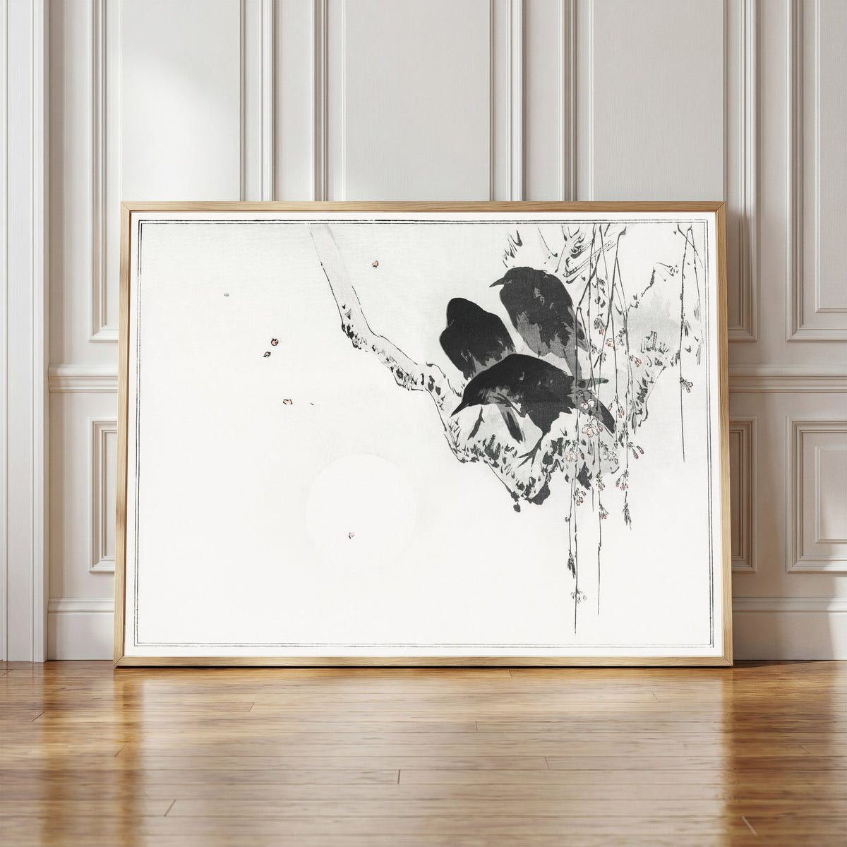 Framed art print of Japanese crows perched on a branch by Watanabe Seitei, in a light wood frame leaning against a panelled white wall