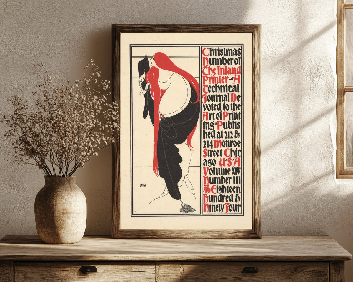 Framed art print of The Inland Printer, Christmas Number, 1894 by Will Bradley, in a dark wood frame leaning on a rustic console beside dried flowers
