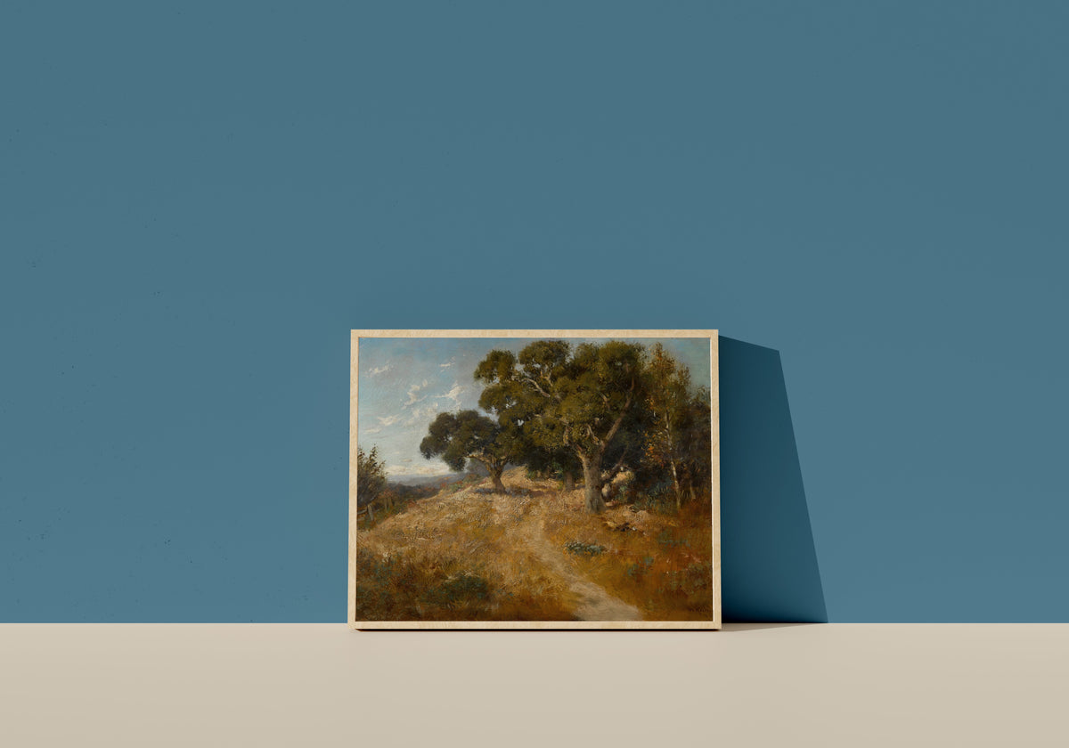 Framed art print of Path through California Oaks by William Keith, in a light wood frame leaning on a blue wall