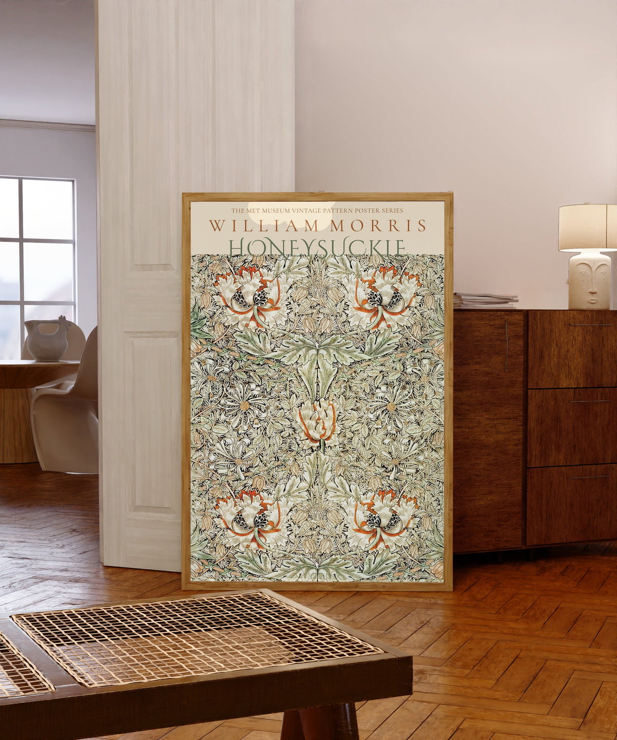 Framed art print of Honeysuckle by William Morris, in a light wood frame leaning in a warm room with a parquet floor
