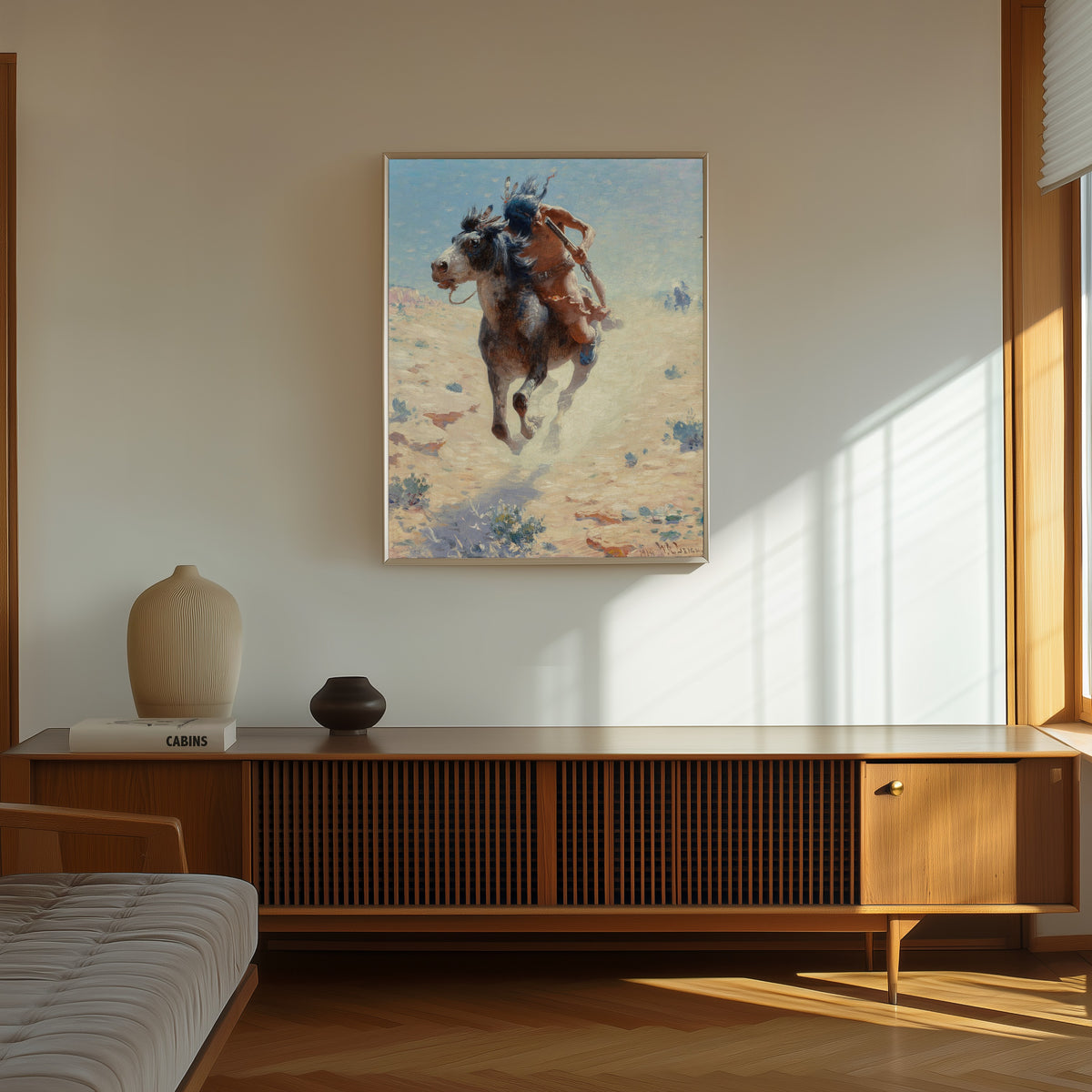 Framed art print of Indian Rider by William Robinson Leigh, in a thin light frame on a sunlit wall above a wooden sideboard
