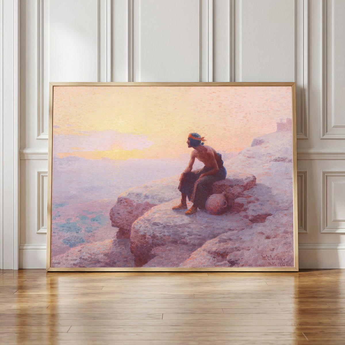 Framed art print of The Water Carrier by William Robinson Leigh, in a light wood frame leaning against a panelled white wall