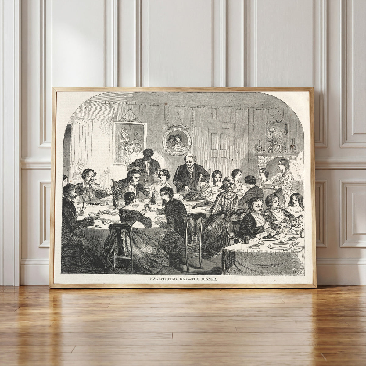 Framed art print of Thanksgiving Day – The Dinner by Winslow Homer, in a light wood frame leaning against a panelled white wall