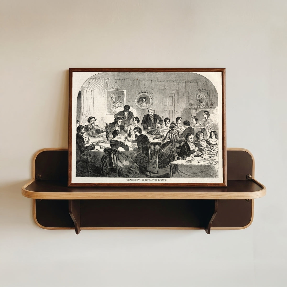 Framed art print of Thanksgiving Day – The Dinner by Winslow Homer, in a dark wood frame resting on a wall shelf