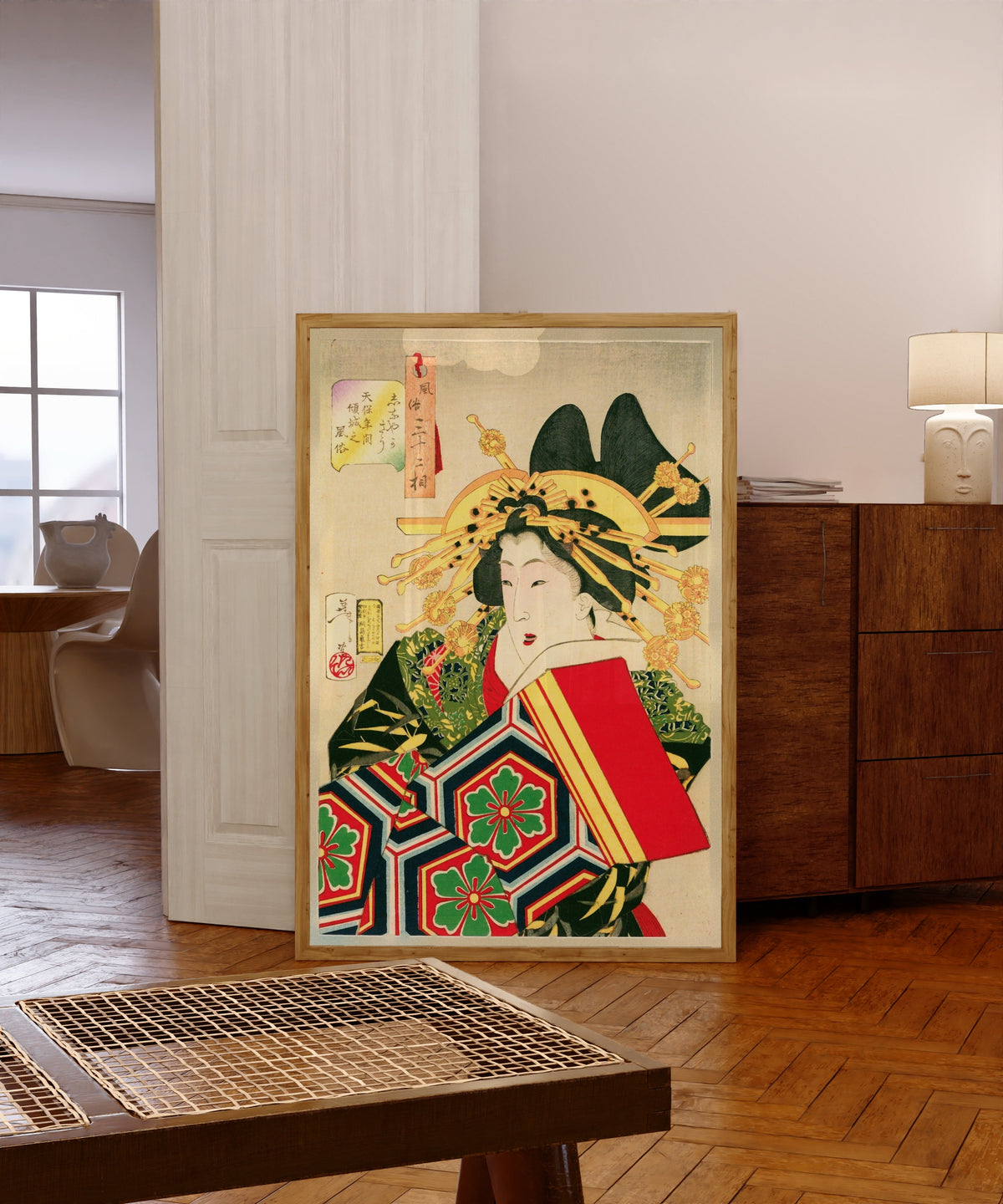 Framed art print of The Geisha by Tsukioka Yoshitoshi, in a light wood frame leaning in a warm room with a parquet floor