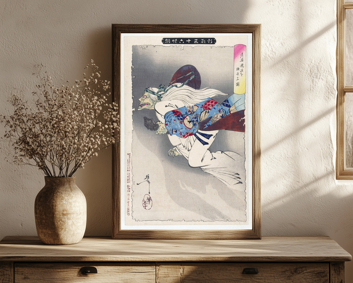Framed art print of The Witch by Tsukioka Yoshitoshi, in a dark wood frame leaning on a rustic console beside dried flowers